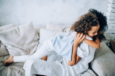 Yukardan bakıldığında, aktif, pozitif, güzel bir kızın evde harika vakit geçirirken nazikçe annesini kucaklaması.