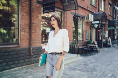 İyimser genç bayan, günlük kıyafetleri ve not defteriyle şehir caddesinde duran iş arkadaşıyla buluşmayı bekliyor.