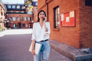 Beyaz gömlekli, ince, zeki bir kadın sokakta yürürken tuğladan binalarla sohbet ediyor, ellerinde klasörler tutuyordu.