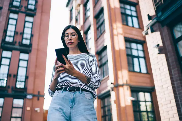 Millennial female blogger using 4g tariff with unlimited internet access for networking social websites and sharing content news to followers, Latino woman in classic glasses texting via application