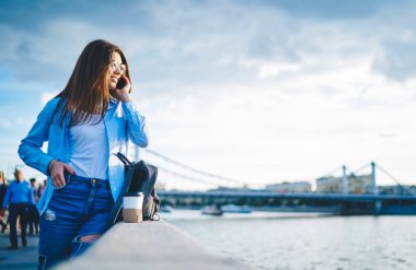 Nehir köprüsünde tatil sırasında eğlenen şık kıyafetli neşeli yeniyetme kız. Hafta sonları ziyarete gelen sıradan kıyafetler içindeki çekici genç bir kadın.