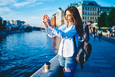 Gündelik hayattaki yetenekli kadın blogcu cep telefonu kamerasıyla blog için çekim videosu çekiyor şehir ortamında duruyor, düşünceli kadın nüfuzlu şehirde gezip cep telefonuyla fotoğraf çekiyor.