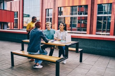 Gündelik giysiler içinde başarılı siyahi kadınların, modern şehrin sokaklarında ortaklarla birlikte proje raporlarını analiz etme stratejisini tartışırken yandan görünüşü