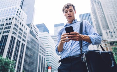 Sörf interneti için 4G kablosuz internet sitesine bağlı mali haberleri kontrol eden erkek tüccar, cep telefonu tebligatı kurarken eşinden e-posta alan evrak çantalı beyaz adam