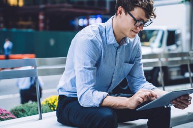 Yakışıklı, gülümseyen bir genç adam, gözlüklü. Meşgul cadde göz atma tabletinde. Manhattan, New York 'ta.
