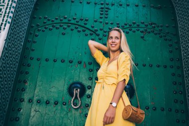 Fas 'ta gezen sarı elbiseli, parlak, mutlu ve güzel bir bayandan. Caddedeki eski renkli binanın yanında dikilip başka tarafa bakıyor.