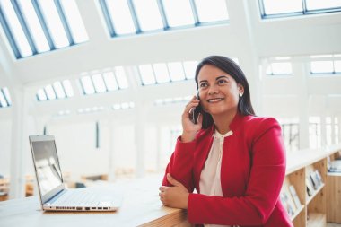 Akıllı telefon konuşmalarıyla yetinen çekici iş kadınlarının yarım boy portresi, iş tartışmalarıyla zengin kadın yönetici, üniversite kütüphanesinde modern teknolojileri kullanarak çalışıyor.