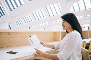 Resmi olarak Kafkas kadın okuyucu elinde kitap tutuyor boş zaman üzerine ilginç denemelerle tatmin olmuş, gülümseyen iş kadını halk kütüphanesinde kişisel eğitim için finans literatürünü kontrol ediyor.