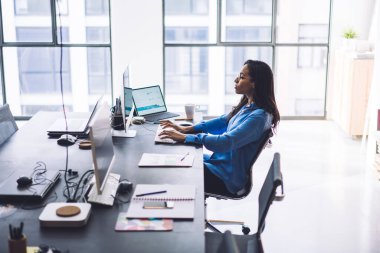 Modern ışık çalışma sahasında bilgisayar klavyesinde aletlerle yazı yazan düşünceli kadın çalışanın yan görünüşü