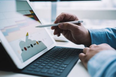 Ofisteki bilgisayar masasında oturan yüzsüz işadamı renkli istatistiksel grafiklerle çalışırken Stylus ile modern tableti tıklatıyor. 