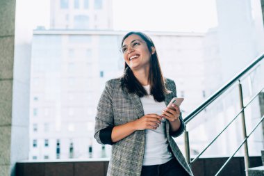 Mutlu beyaz hippi kız gülüyor cep telefonundan komik bir mesaj alıyor şehir planında duruyor, gülümsüyor binlerce yıllık güzel bir kadın akıllı telefondaki bankacılık uygulamasından memnun. 