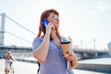 Başarılı genç bayanın günlük kıyafetleri ve kağıt işleriyle dolu bardakları vardı. Taze içki içiyordu, telefonla iş arkadaşıyla konuşuyordu. Gezinti alanında yürüyordu.