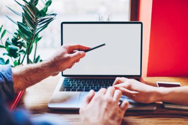 Tanımlanamayan serbest çalışanlar, modern kafede uzak projeler üzerinde çalışırken boş ekran ile bilgisayardaki verileri tarıyor ve analiz ediyorlar.