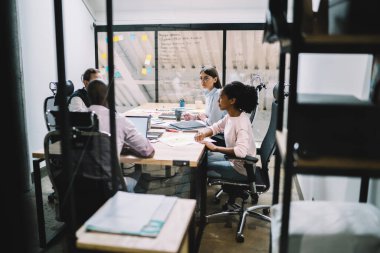 Toplantı odasındaki kırtasiye malzemeleriyle masanın etrafında önemli bir konuşma sırasında şirketin geleceğini planlayan çeşitli zeki profesyonel çalışanlardan oluşan bir grup.