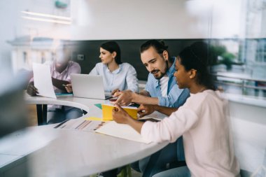 Çeşitli takımlar proje üzerinde çalışıyor ve belgeleri incelerken birbirlerine danışıyorlar ve ışık ofisinde buluşmada fikir geliştiriyorlar.