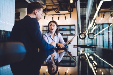 Çeşitli odaklı iş arkadaşları, tablet kullanırken ve modern ofis odasındaki masada otururken iş projelerini tartışıyor ve üzerinde çalışıyorlar.