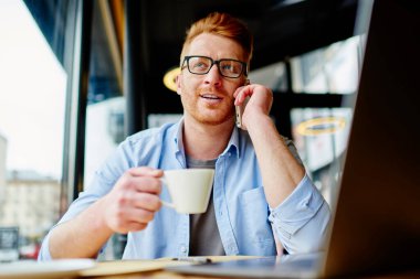 İyimser bir adamın, gündelik kıyafetleri ve gözlükleriyle akıllı telefondan konuşmasının, sıcak bir şeyler içmesinin, kafeteryada oturup gözlerini kaçırmasının.