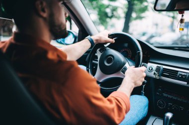 Modern arabada oturan ve arka planda bulanık direksiyon kullanan sakallı erkek sürücünün arka plan görüntüsü.