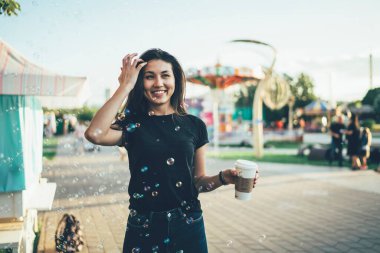 Çekici bir kadın eğlence parkında tatil yaparken mutlu duygular hissediyor, neşeli gülümseyen hippi kız şehir festivalinde yaz tatilinde hava baloncuklarıyla eğleniyor.