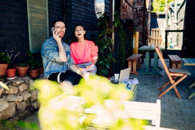 Mutlu iş arkadaşları tavan arası kafeteryasında iş birliği yapıyor. Birlikte vakit geçiriyorlar. Moda giyinmiş adam cep telefonu yapıyor.