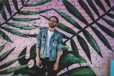 Milenyum etkileyicisinin yarım boy portresi şık kıyafetler giyip fotoğraf alanına yakın poz vererek medya içeriği yaratmak için boş vakitlerin tadını çıkarıyor. Kot ceketli yakışıklı nesil Y kameraya bakıyor.