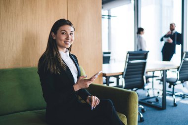Takım elbiseli güzel Asyalı ofis çalışanı, ara verdiğimizde kameraya bakıp gülümsüyor.
