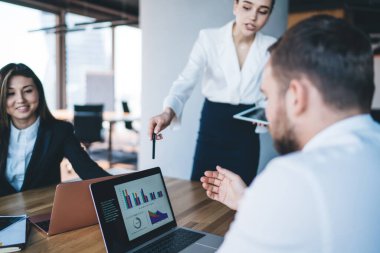 Resmi olarak ürün ortakları konuşurken ve dizüstü bilgisayar kullanırken çağdaş ofiste bulanık arka planda ahşap masada oturuyorlar.