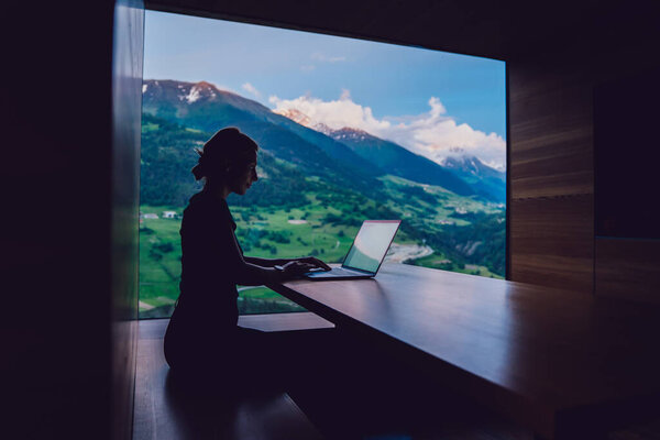 Опытная женщина цифровой кочевник работает удаленно создание путеводитель по высоким горам для обмена с последователями в социальных сетях, подключенных к 4g Интернет, квалифицированный фрилансер набрав текст на ноутбуке