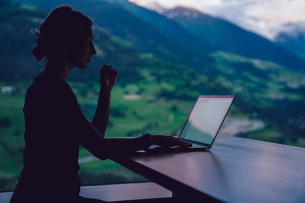 Силуэт тысячелетней женщины проверки настройки на ноутбуке устройства, сидя за столом и используя Wi-Fi веб-соединение для онлайн-связи, женщина цифровой кочевник делает внештатную работу во время отпуска