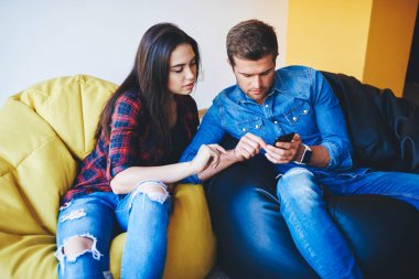 Beyaz kadın ve erkek, akıllı telefon uygulaması ile alışveriş yapıyor. Seçilen eşyaları iletişim kuruyor. Erkek ve kadın hipsterler, ara verildiğinde birlikte çalışma alanına yeni güncellemeler kuruyor.