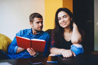 Kameraya bakan neşeli beyaz kadın öğrencinin portresi erkek arkadaşıyla sohbetin keyfini çıkarın, aşık çift notlarda gelecek için planlarını tartışın birlikte okuyun.