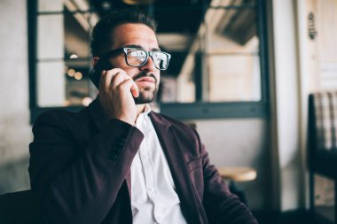 Ciddi bir beyaz erkek girişimci ciddi bir cep telefonu sohbeti yapıyor, resmi kıyafetli dalgın bir işadamı cep telefonu konuşmasına odaklanmış, başka bir yere bakıyor.