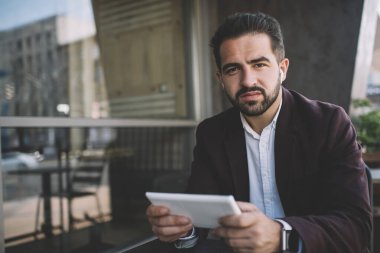 Çevrimiçi oyun oynamak için dijital tablet kullanan yakışıklı beyaz sakallı adamın portresi dijital cihazlarla boş zaman harcıyor, ciddi bir erkek girişimci resmi kıyafet giymiş, touchpad tutuyor.