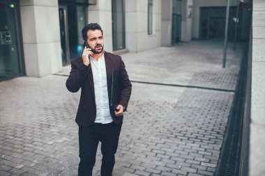 Resmi takım elbiseli, akıllı telefon kullanarak iş arkadaşınla konuşan, caddeleri gözetleyerek projenin stratejisini tartışan etnik bir adama dikkat et.