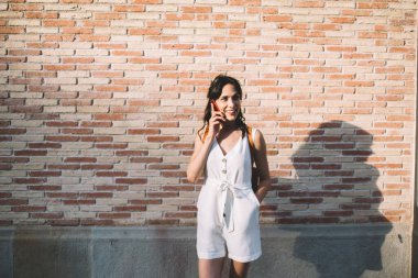 Güzel bir kadın cep telefonuyla konuşuyor ve gülerek uzaklaşıyor hem de öğleden sonra sokakta dikilirken.