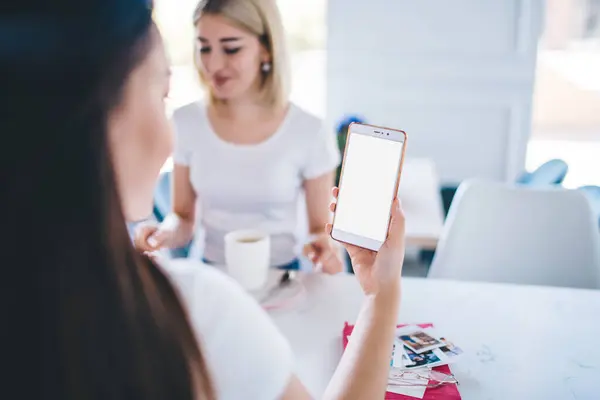 在现代的白色自助餐厅 快乐的年轻女性穿着白色T恤坐在桌旁 一边用手机聊天一边喝咖啡 — 图库照片
