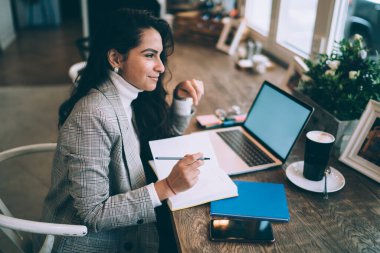 Kafeteryada ders kitaplarına not almak için not defteri kullanan genç beyaz bir kadın. Moda bir çalışma alanında dizüstü bilgisayarın başında oturan mutlu bir kız öğrenci.