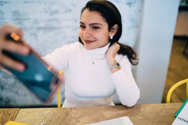 Beyaz kadın 20 'li yaşlarda cep telefonu uygulaması ile video blogları için 4G kablosuz bağlantı kuruyor, güzel kadın nüfuzlu internet ağı kurarken vlog içeriği vuruyor.