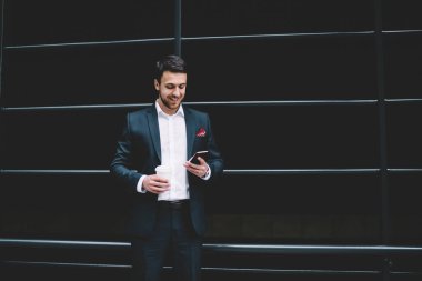 Resmi takım elbiseli, güler yüzlü, akıllı telefon konuşmaları yapan, arkadaşlarıyla sohbet eden modern şehrin sokaklarında sıcak içecek içen bir adam.