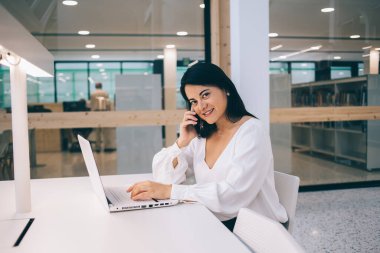 Çekici, kendine güvenen bir iş kadınının portresi dizüstü bilgisayarında modern modaya uygun bir şekilde yazarken telefon görüşmesi yapıyor. 20 'li yaşlarda genç bir yönetici hücresel sırlarını internette paylaşıyor.