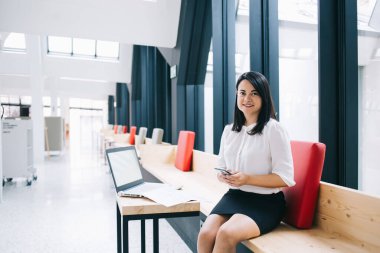 Resmi giyinen 30 'lu yaşlardaki kendine güvenen genç bir kadın modern ofiste teknolojiyle çalışan kısa mesajlar gönderiyor, başarılı bir kadın yönetici postayı kontrol ediyor ve araştırma için dizüstü bilgisayarla çalışıyor.