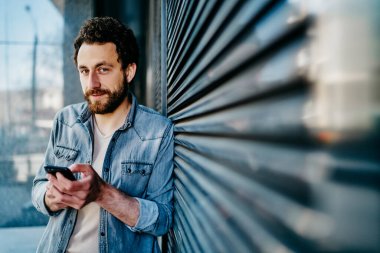 Yakışıklı, kendine güvenen, günlük kıyafetlerle serbest çalışan, kameraya ilgiyle bakan, bulanık çizgili duvarlara ve kentsel çevreye karşı duran ve şehirdeki akıllı telefonlarla etkileşim halinde olan biri.