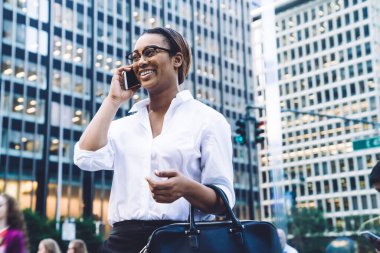 Gözlüklü, beyaz gömlekli, akıllı, genç, zeki iş kadını. Meşgul şehir caddesinde dikilirken telefonla konuşuyor.