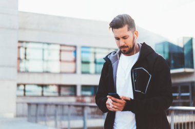 Kulaklıklı, kalın elbiseli, sakin bir adamın altında müzik dinleyerek sokakta koşuya hazırlanıyor.