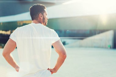 Arkaya bakan güçlü koşucunun parlak bir günde güneşli bir meydanda antrenman yaptığını düşün.