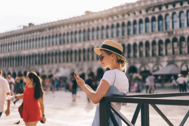 Mobil cihaz ile saman şapka ağı kuran son moda kadın turist İtalyan galerileri hakkında bilgi okumak için seyahat uygulaması, tarihi merkezleri keşfederken Kafkasyalı kadın otel odası rezervasyonu