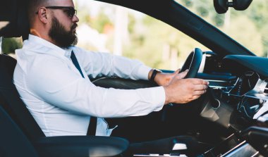 Şehirdeki iş toplantısına gitmek için kiralık araba kullanan sakallı erkek girişimcinin yan görüntüsü, araba süren beyaz adam konforlu araç yolculuğunun keyfini çıkarıyor.