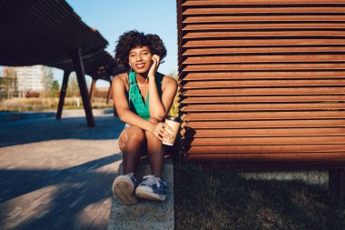 Çekici, koyu tenli hippi kız dışarıda boş zamanın tadını çıkarıyor. Kulaklıkla müzik dinliyor, kahve içiyor. Güzel, gülümseyen bir Afro-Amerikan kadını.