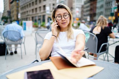 Çin kadın milenyumu cep telefonu başvurusu ile dolaşırken, Asyalı kadın görüş koruması için arıyor sokak kafesinde boş zamanlarında uluslararası telefon görüşmesi yapıyor.