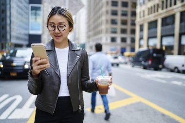 Milenyum Deri ceketli bir kadın, şehirde boş zamanlarında ağ uygulaması kullanarak yeni sosyal yayınlar yapıyor, Çinli kadın blogcu takipçileriyle akıllı telefon sohbeti yapıyor.